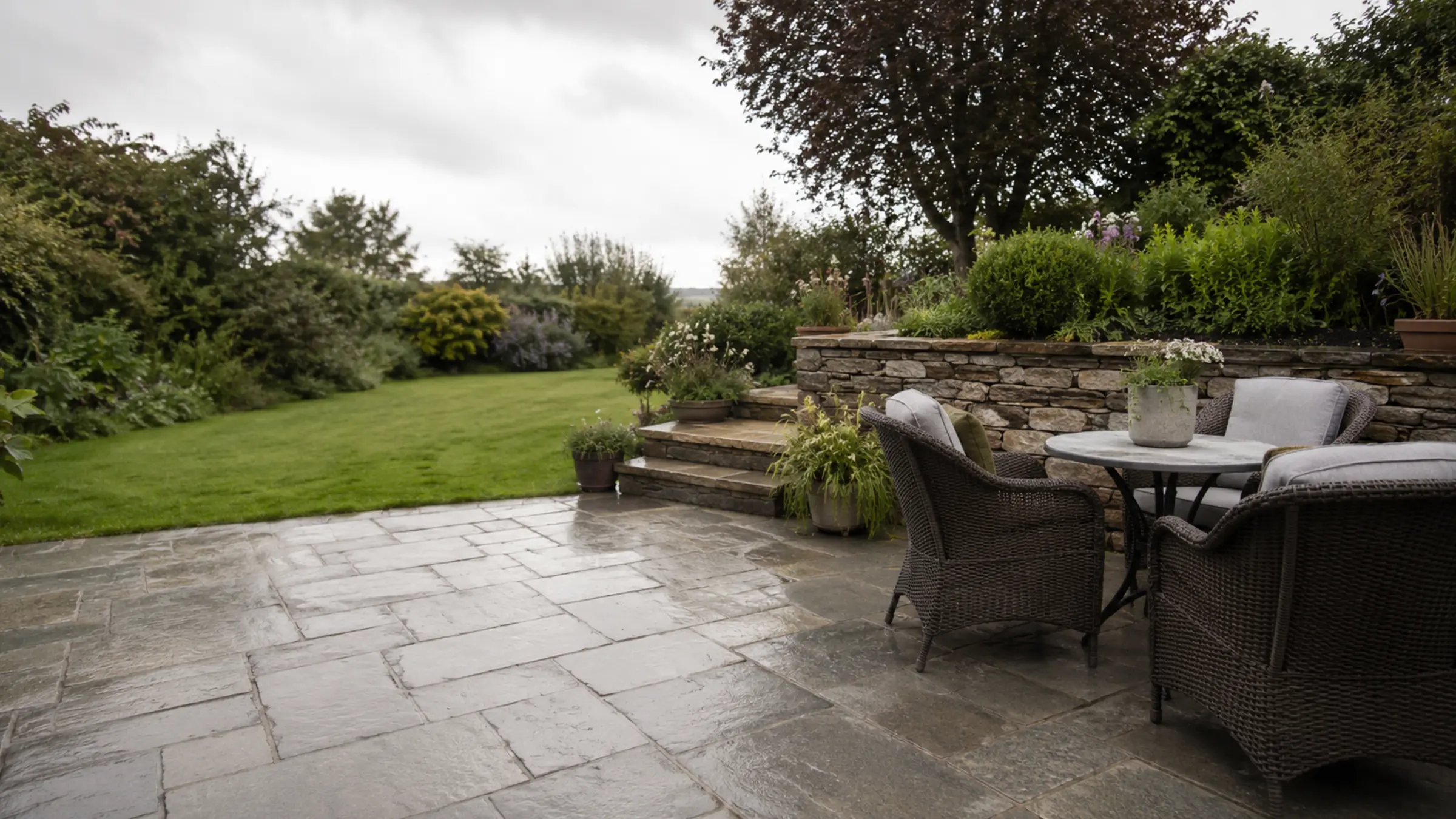 A stone patio seating area at the back of a house