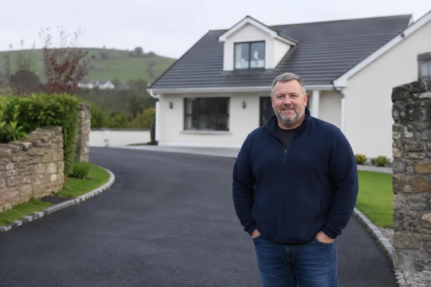 A homeowner standing on a newly finished driveway outside their home in Ireland