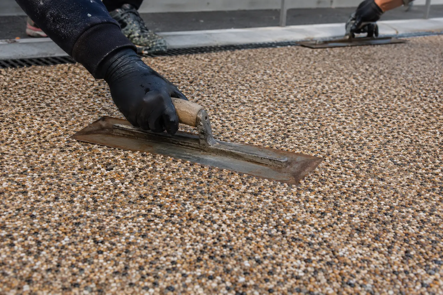 Contractor spreading resin bound aggregate on a prepared base